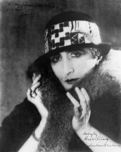 La prima e più celebre fotografia di Rrose Sélavy, scattata da Man Ray nel 1921. La donna è vestita con una pelliccia e un cappello a motivi geometrici.
