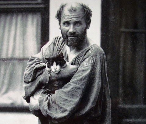 Fotografia d'epoca che ritrae Gustav Klimt con un gatto in braccio di fronte il suo atelier.